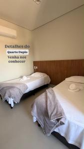 two beds in a hotel room with towels at Hotel Bom Gosto in Taiobeiras