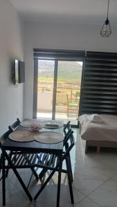 a table and chairs in a room with a window at Vana's Apartments in Sarandë +6 photos