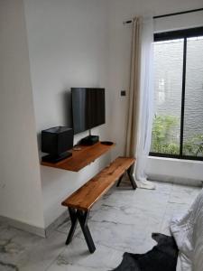 a living room with a wooden bench and a flat screen tv at Villa Blanche in Cotonou