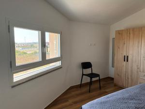 a bedroom with a chair sitting next to a window at Casa Demelas in Stintino