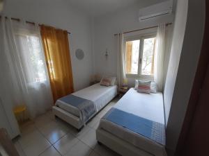 a bedroom with two beds and a window at Kampos Rooms in Palaiochora