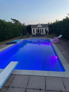 a large blue swimming pool with a house in the background at Aelybryn in Llangwyryfon