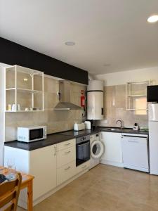 a kitchen with white cabinets and a stove top oven at Alojamento das cantarinhas in Bragança