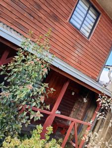 a red house with a plant in front of it at Hostal y Cabañas Guaje in Valdivia