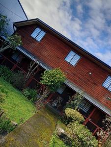 a red brick house with white windows on it at Hostal y Cabañas Guaje in Valdivia