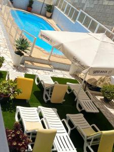 a group of chairs and an umbrella next to a swimming pool at Casa Godinho in São Martinho do Porto
