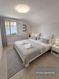 a white bedroom with a large bed and a window at Mon Bijou Chalet au Lac Alpin in Thun