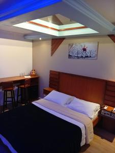 a bedroom with a bed and a desk and a table at Motel Avenida (Adult Only) in Gramado