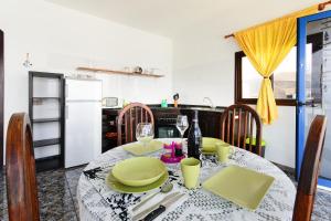 a kitchen with a table with green plates and wine glasses at Caleta Blue House - Macaronesiahome in Caleta de Caballo +18 photos