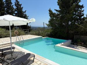 a swimming pool with an umbrella and a table and chairs at AMYGDALIA in Vlachopoulátika
