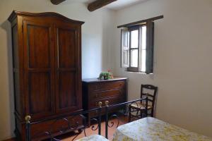 a bedroom with a wooden cabinet and a bed and a window at Loggia dei Barbaggianni in Torraca