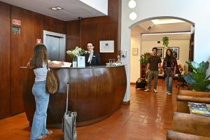a woman standing at a reception desk in a lobby at Hotel Principe Real in Lisbon