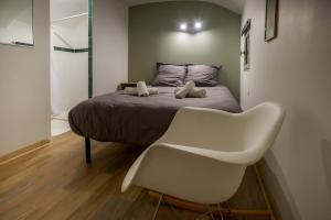 a bedroom with a bed and a white chair at Le Cocon Vouté, air-conditioned in Saint-Laurent-des-Arbres