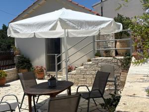 a patio with a table and chairs under a white umbrella at AMYGDALIA in Vlachopoulátika