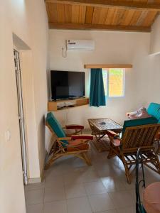 a living room with chairs and a table and a television at Le Clos Rivière in Ndangane