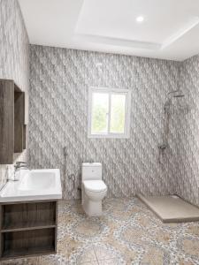 a bathroom with a toilet and a sink and a window at Peace apartment in Brufut