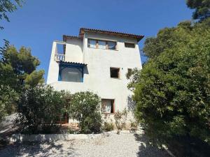 a large white building on a hill with trees at Natasa private garden apartment in Polychrono