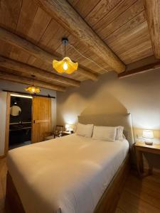 a bedroom with a large white bed and wooden ceilings at A Barreira -Lar da cima- in Folgoso