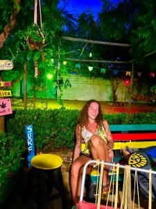 a woman sitting on a bench at night at Canoa Roots Hostel & Camping in Canoa Quebrada