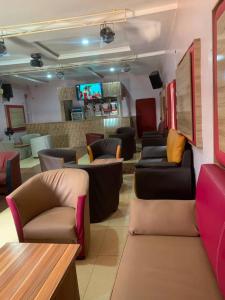 a waiting room with couches and chairs and a tv at Luxritel Hotel Abuja in Kajewole