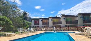 a swimming pool with chairs and a building at Arco Iris Chales II in Maresias