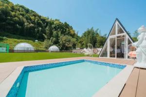 a swimming pool with a house with a mountain in the background at Camp studio - Vacation STAY 89015v in Ichihara