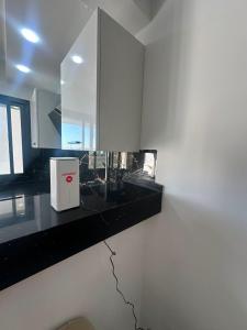 a white kitchen with a black counter and a window at Appartement de luxe in Tunis