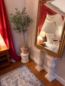 a mirror in a room with a bed and a plant at L'Escale Romaine - Expérience Antique Unique - Centre Historique Orange in Orange