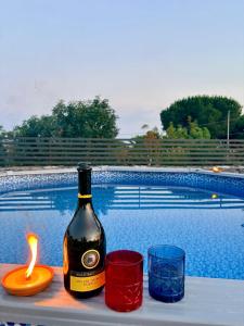 a bottle of wine and two candles next to a swimming pool at Villa le dalie in Mascalucia