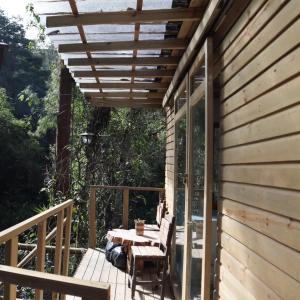 a wooden deck with a table and a wooden pergola at Kai Ecoglamping in El Peñol