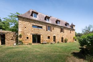 an old stone house with a roof on a field at Domaine de Cantegrel - Gîtes de Charme et Suite Troglodyte en Périgord in Vitrac