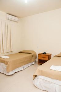 Habitación de hotel con 2 camas y mesa en Fragata Apart Hotel en Marília