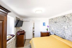 a bedroom with a yellow bed and a stone wall at Casa Isca in Trentinara