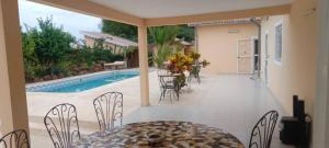 a patio with a table and chairs and a pool at Le Clos Rivière in Ndangane