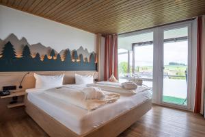a large bed in a room with a large window at Wellnesshotel Sonnenhof & Sonnhalde in Ühlingen-Birkendorf