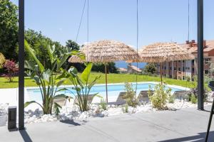 a pool with two straw umbrellas and some plants at Prado Essence in Sanxenxo