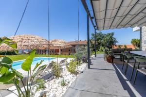 a patio with a pool and tables and straw umbrellas at Prado Essence in Sanxenxo