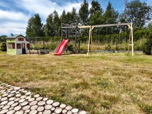 a playground with a red slide in a field at Domki Bosman in Dziwnówek