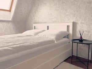 a bedroom with a white bed with a side table at Astrum Apartman in Egerszalók +13 photos