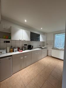 a large kitchen with white cabinets and a window at Gemütliche Ferienwohnung in Worbis in Worbis +8 photos