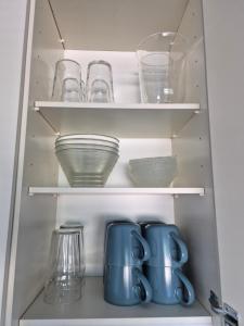 a cupboard filled with bowls and glasses at Apartment with private sauna in Loimaa