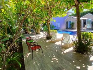 a patio with chairs and trees next to a pool at Hotel Jaco Lodge in Jacó