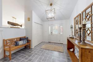 a living room with white walls and a table and a bench at Salty Way in Ocean Pines