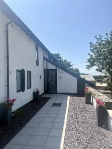 a white building with a door and some flowers at The Properties at Plas Menai in Caernarfon
