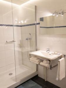 a white bathroom with a shower and a sink at Hôtel Au Val De Saône PARKING GRATUIT in Sathonay-Camp