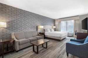 a hotel room with a bed and a couch and chair at Best Western PLUS Franklin Square Inn in Troy
