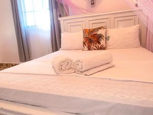 a bed with a towel and pillows on it at KL beach road Diani in Ukunda