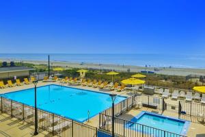 a pool with chairs and umbrellas and the beach at Plaza 211 in Ocean City
