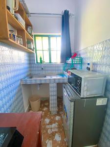 a small kitchen with a sink and a microwave at KL beach road Diani in Ukunda