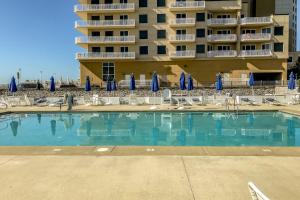 a swimming pool in front of a hotel with chairs and umbrellas at 5 Whitecap in Ocean Pines